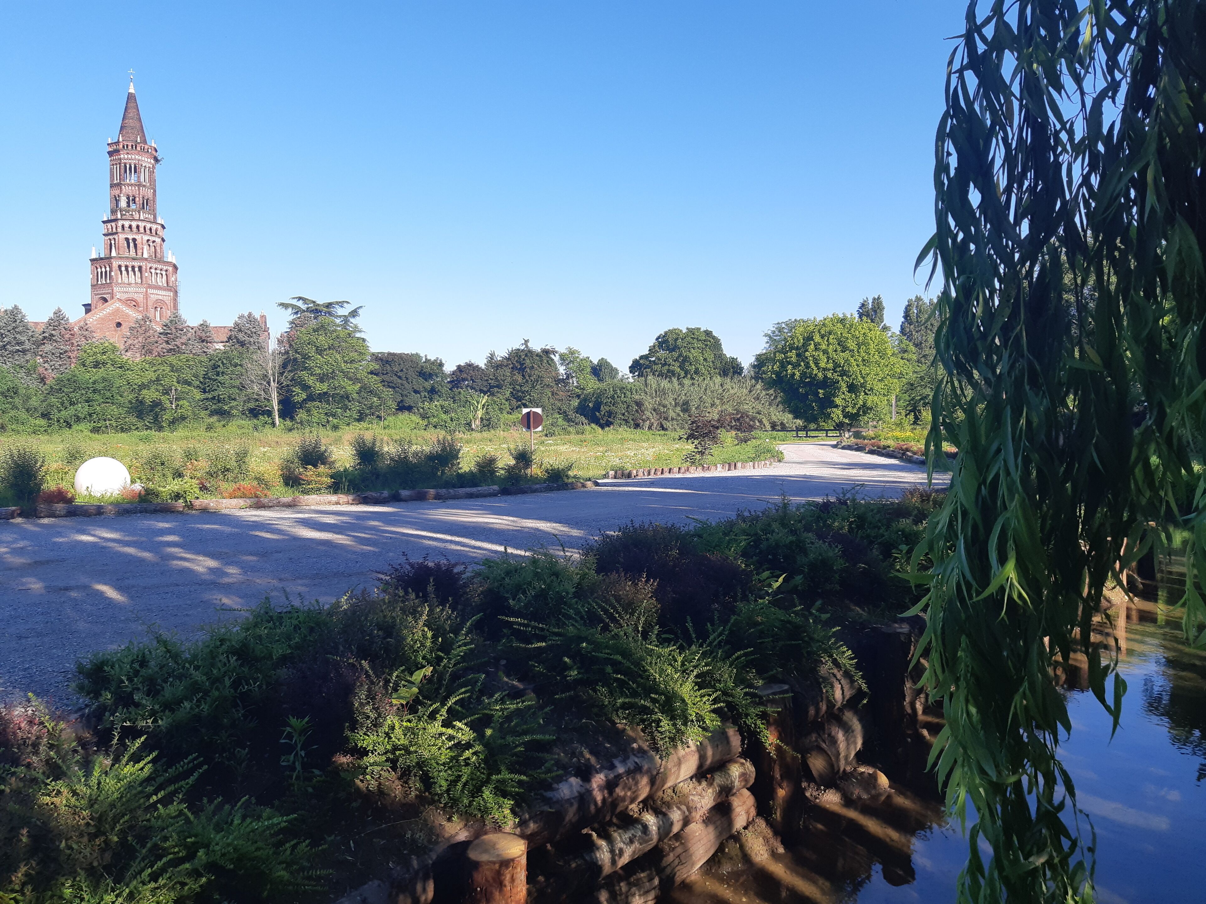 A park with a pond, a large white sphere, and a historic tower in the background.