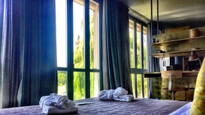 A neatly made bed with a purple quilt, a window with curtains, and a shelf with a lamp and a can. - Boutique Hotel Borgo Nuovo (Milan)