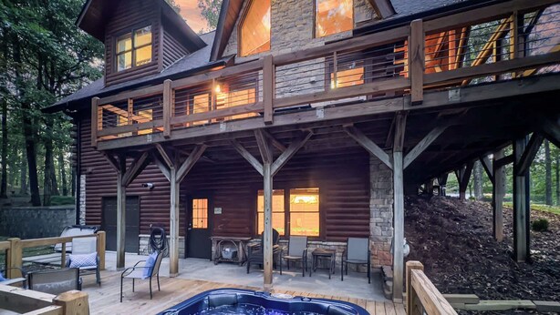 A log cabin with a hot tub, outdoor seating, and a stone fireplace. - Rustic Retreat - view-pets-games-hot tub-fire pit (Mineral Bluff)