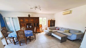 A living room with a dining table, chairs, a sofa, and a cabinet. - T3, in house 3 min from the beach, 5mn from the village on foot, very quiet. (Saint-Florent)