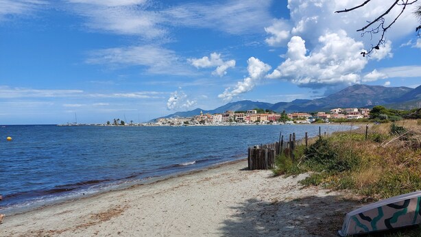 A beach with a sandy shore, a wooden fence, and buildings in the background. - T3, in house 3 min from the beach, 5mn from the village on foot, very quiet. (Saint-Florent)