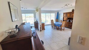 A spacious kitchen with a long counter, a dining area with a table and chairs, and a view through large windows. - T3, in house 3 min from the beach, 5mn from the village on foot, very quiet. (Saint-Florent)