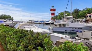 A marina with boats docked, a lighthouse in the background, and lush greenery in the foreground. - 3 Bedroom retreat with private pool (Hilton Head Island)