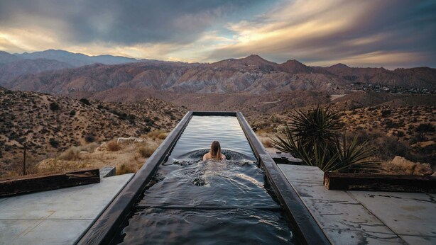 A person in a narrow water channel with a mountainous landscape in the background. - Hawkeye Dome • 112 Acres, Pool & Spa, Epic Views (Yucca Valley)