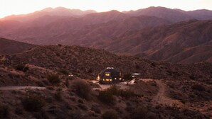 A desert landscape with a single house featuring a dome-like structure, surrounded by rugged hills and sparse vegetation. - Hawkeye Dome • 112 Acres, Pool & Spa, Epic Views (Yucca Valley)