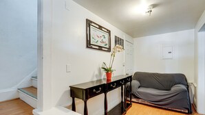 Una sala de estar con un sofá gris, una consola de madera oscura con cajones, una planta en maceta y un cuadro en la pared.
