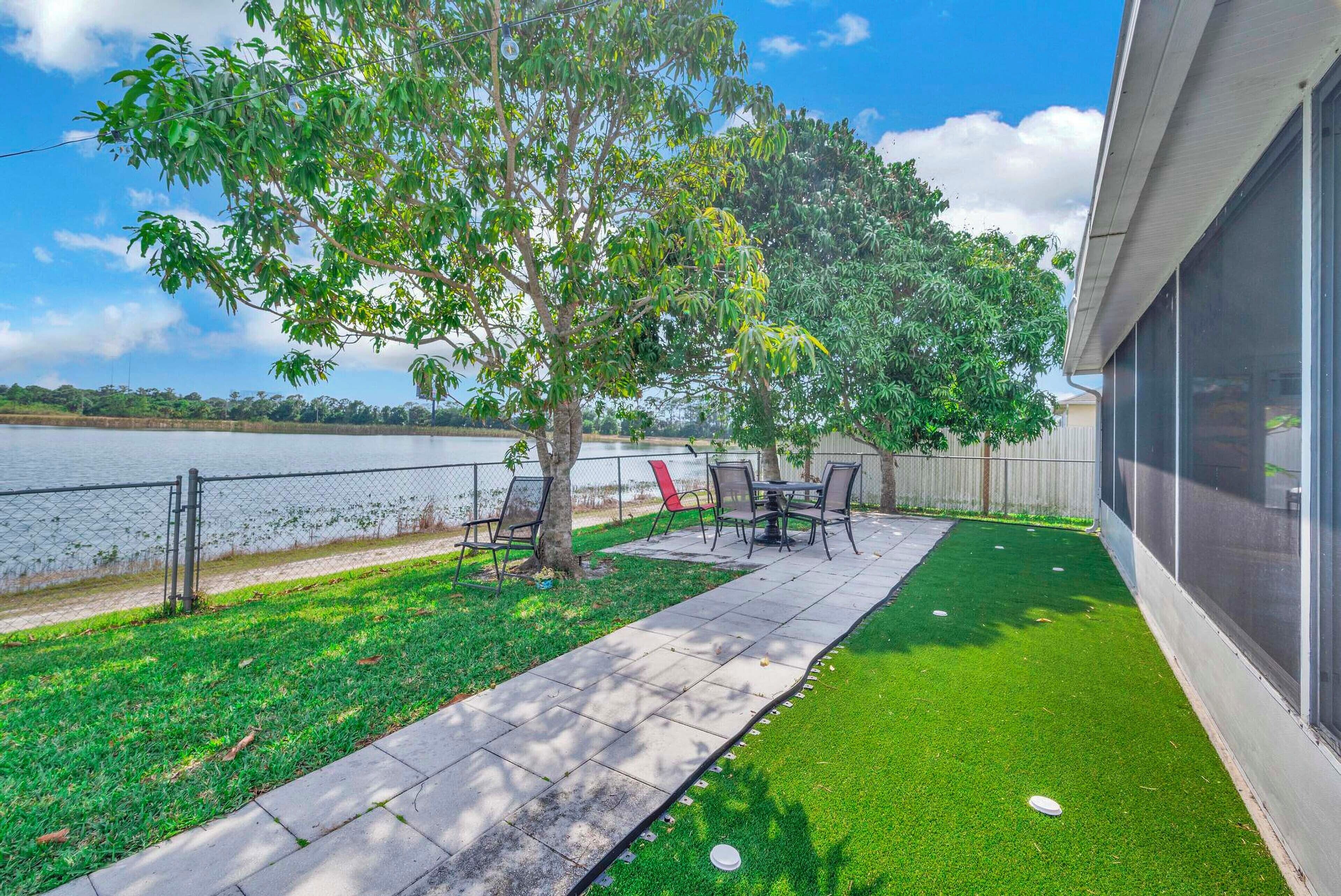 A patio area with a table and chairs, a lawn, and a view of a body of water.