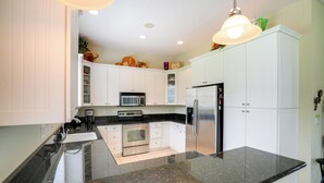 A modern kitchen with white cabinets, a granite countertop, stainless steel appliances, and a pendant light. - Swim & Golf: Family Home 2 Mi to Clover Park! (Port Saint Lucie)