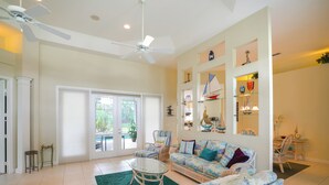 A spacious living room with a large sofa, two armchairs, a glass coffee table, and a ceiling fan. - Swim & Golf: Family Home 2 Mi to Clover Park! (Port Saint Lucie)