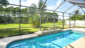 A swimming pool with a view of a grassy yard and trees. - Swim & Golf: Family Home 2 Mi to Clover Park! (Port Saint Lucie)