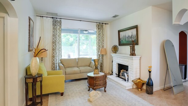 A living room with a yellow sofa, a white fireplace, and a large window with curtains. - 5 Mi to Boating! Port St Lucie Home w/ Backyard (Port Saint Lucie)