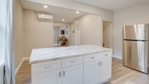 Una cucina moderna con mobili bianchi, un piano di lavoro in marmo e un frigorifero in acciaio inossidabile.
