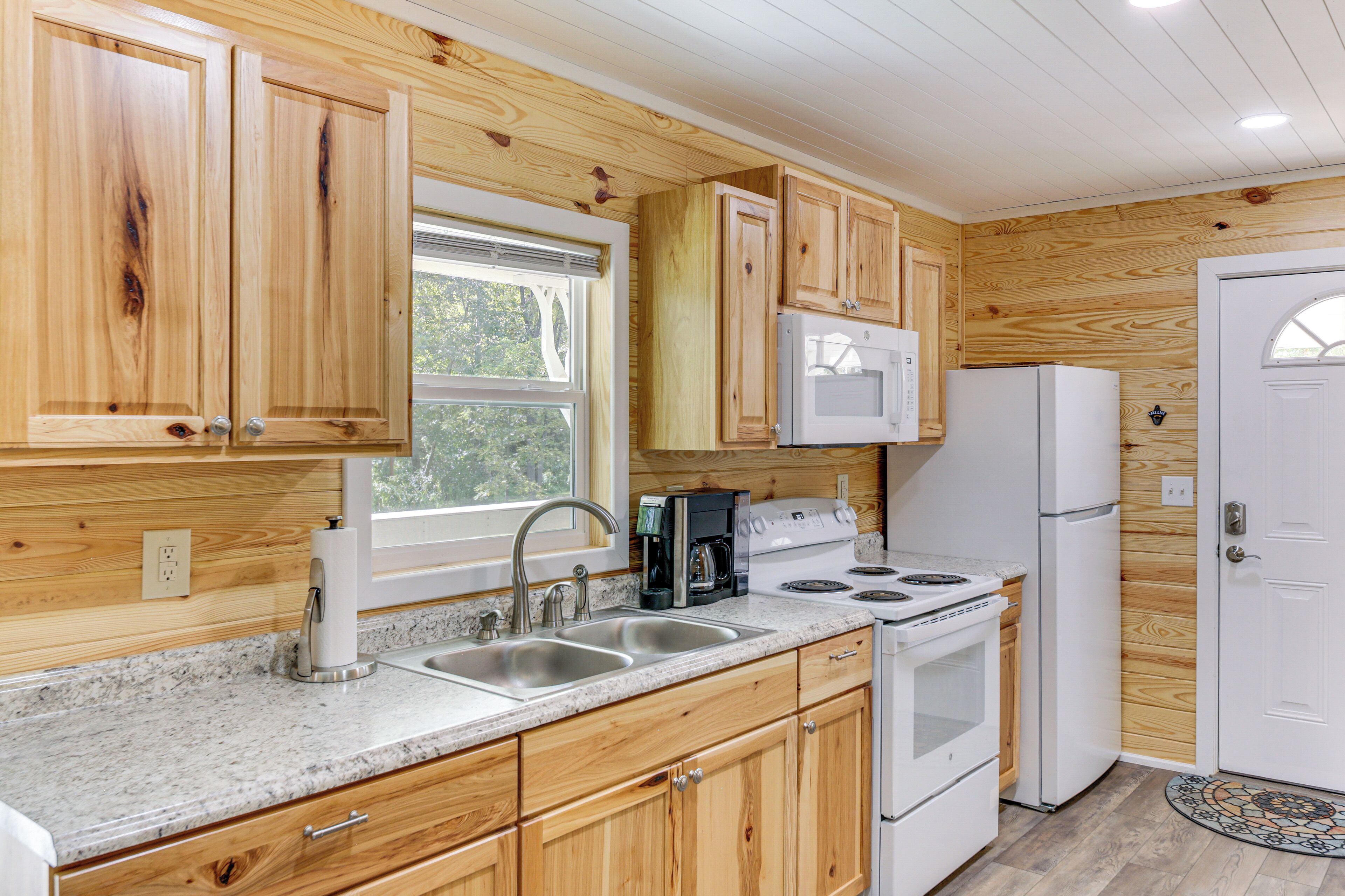 A kitchen with wooden cabinets, a white refrigerator, a stove, and a sink.