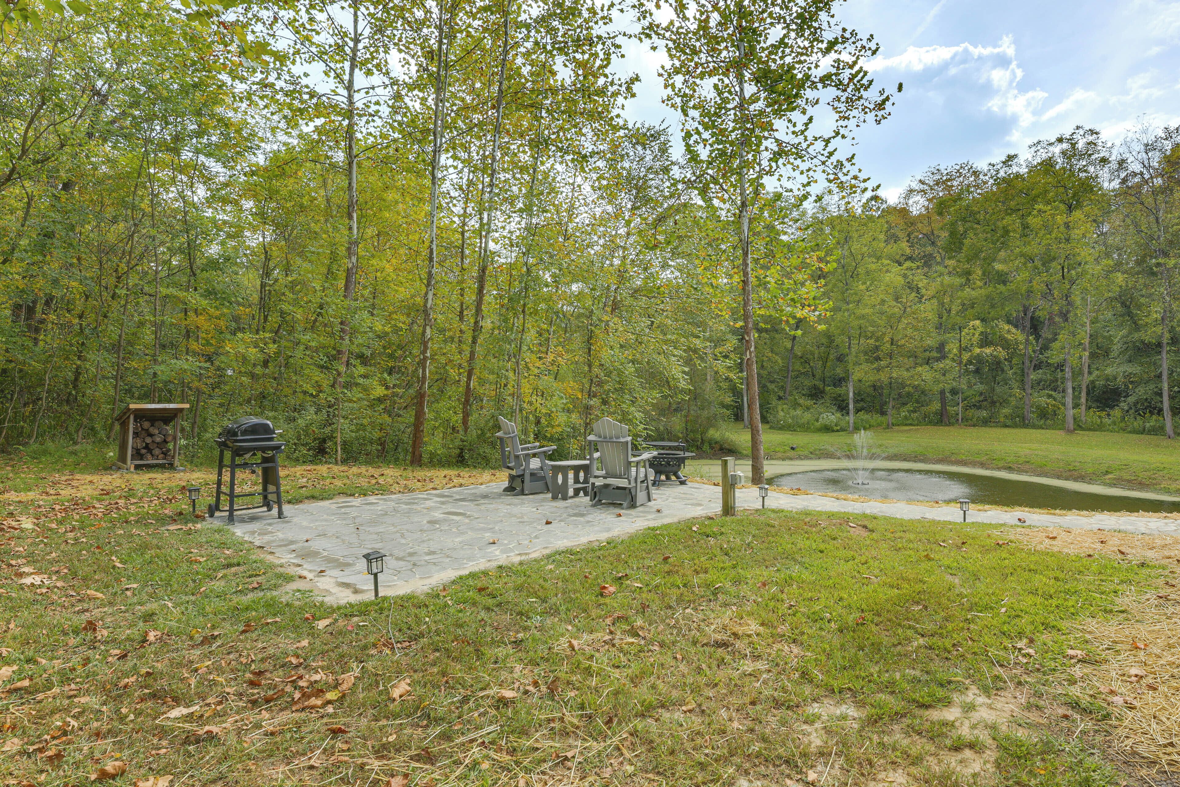 A patio area with outdoor furniture, a grill, and a pond.