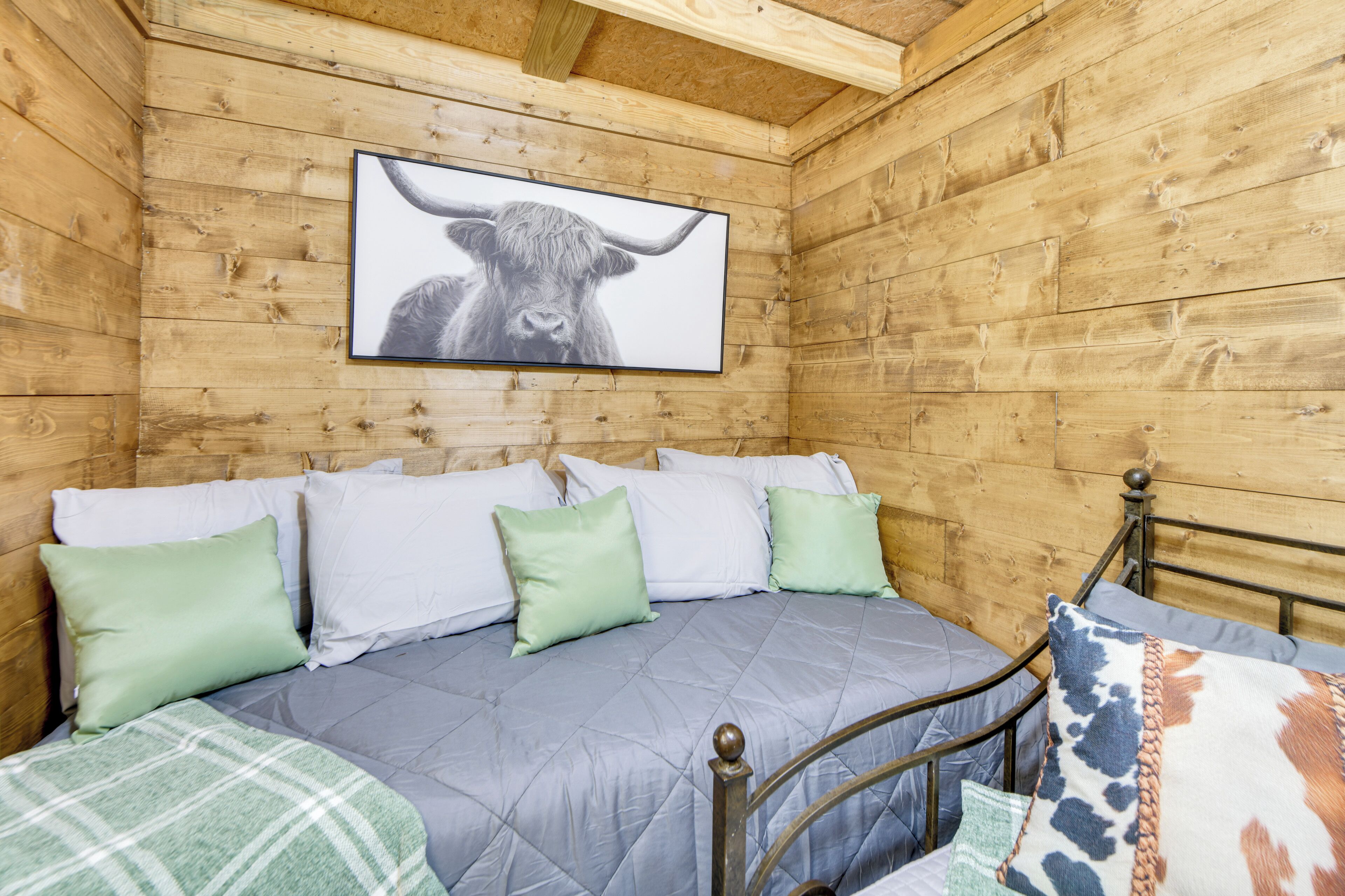 A wooden cabin room with a bed, pillows, and a framed picture on the wall.