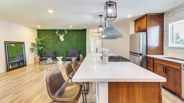 Una cocina moderna con una isla central, armarios de madera y un refrigerador de acero inoxidable.