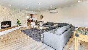 Una sala de estar moderna con un sofá gris, una mesa de fútbol, una chimenea y una pared de piedra.