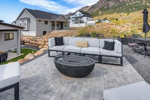 En patio med en grå sofa, sorte og beige hynder og en stor sort pejse.
