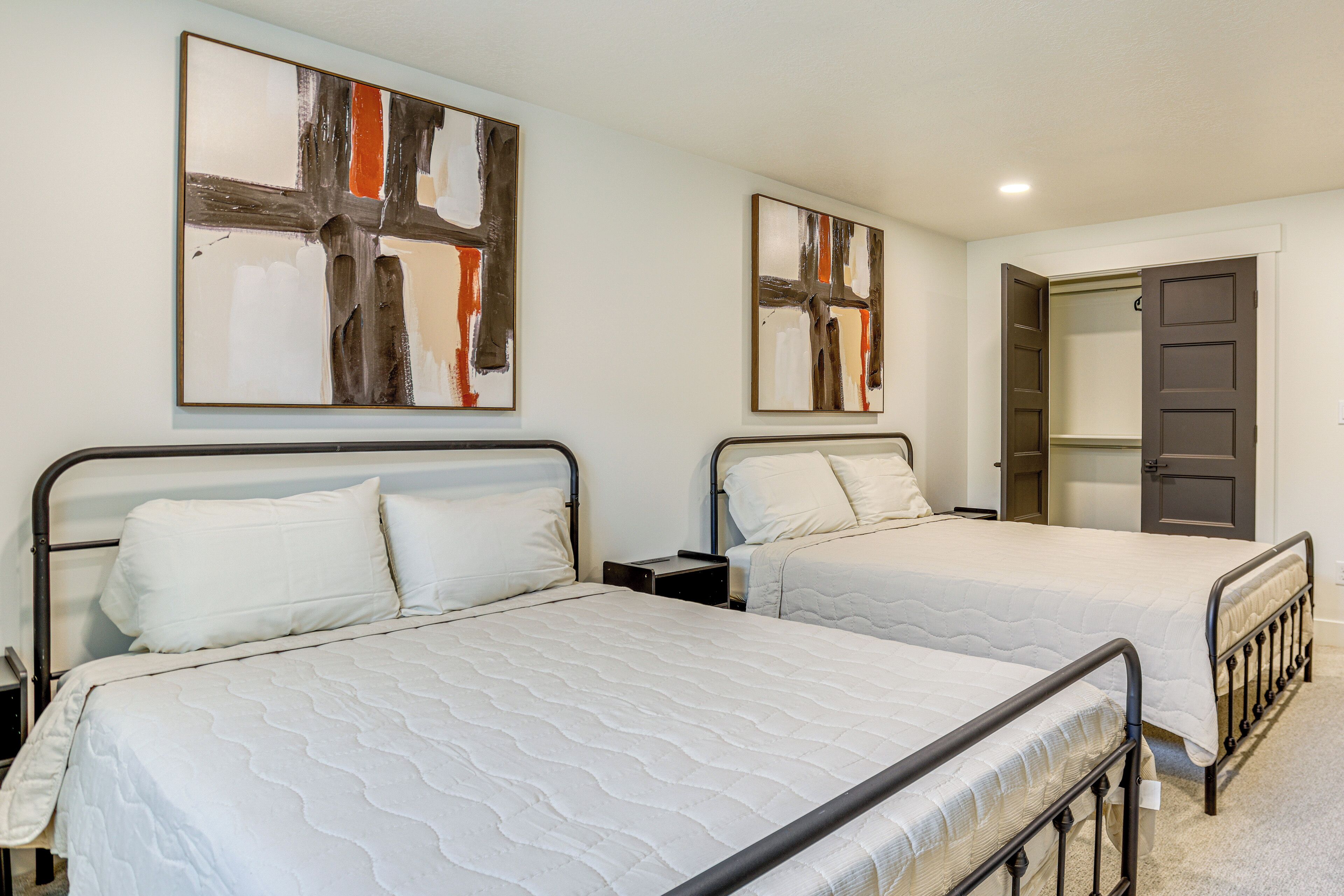 A bedroom with two beds, each with a white mattress and headboard, and a nightstand between them.