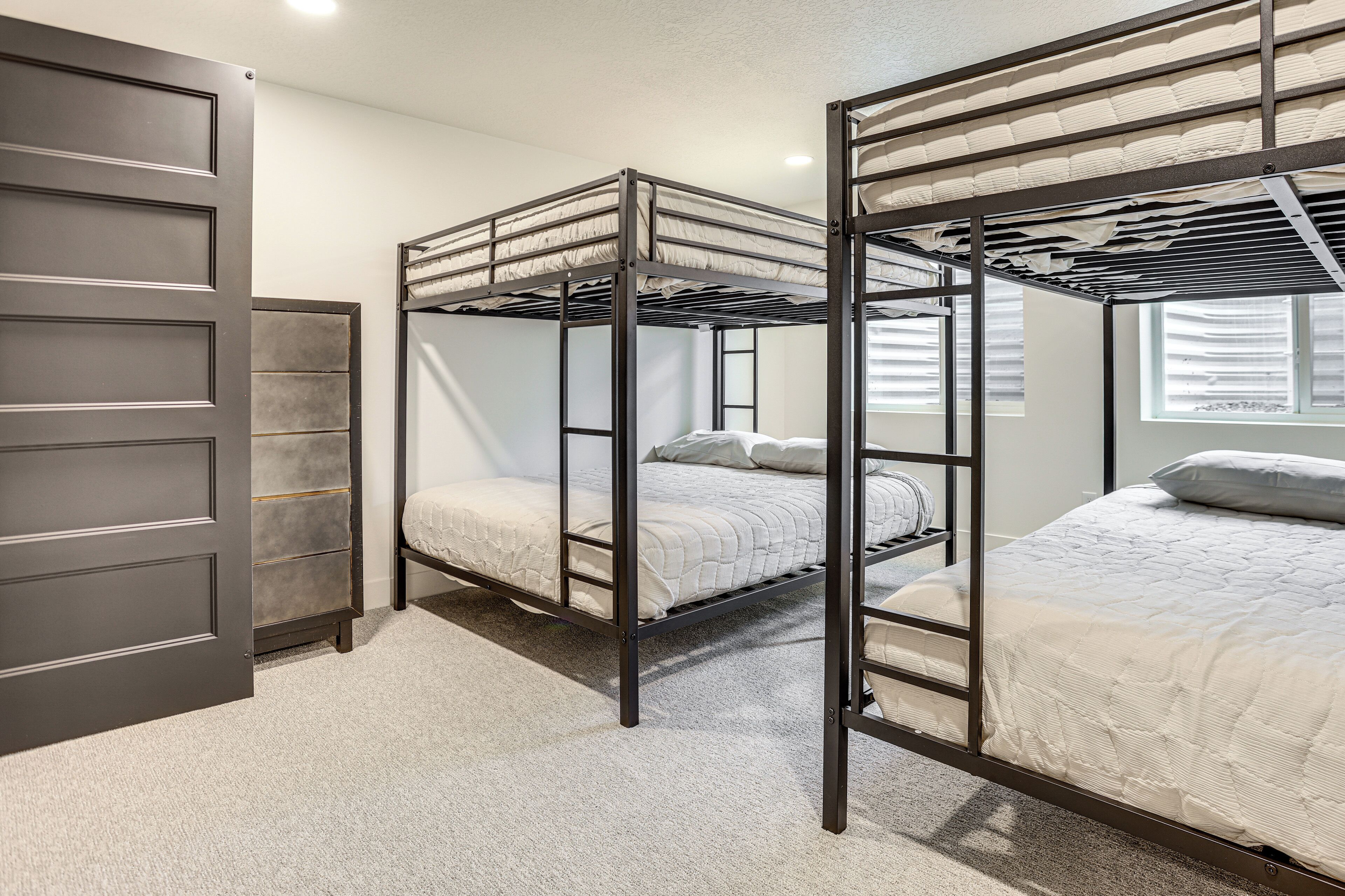 A bunk bed room with a door, a window, and a carpeted floor.