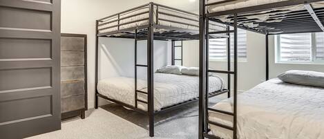 A bunk bed room with a door, a window, and a carpeted floor.