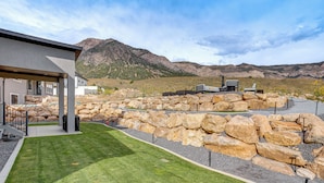 A modern building with a covered patio area, a well-maintained lawn, and a rocky landscape in the background. - Pool Table & Putting Green! Scenic Ogden Escape (Ogden)
