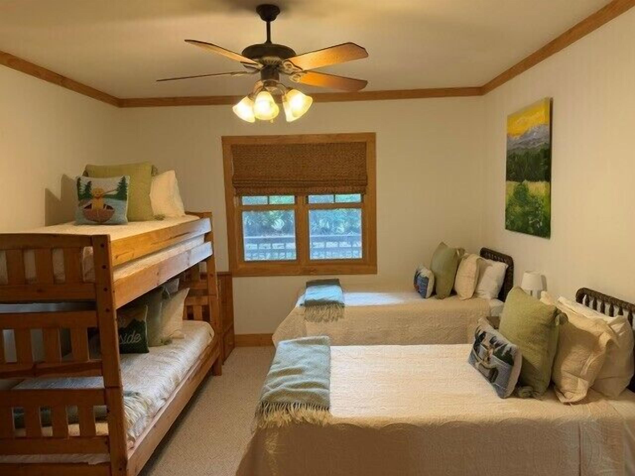 A bedroom with bunk beds, a ceiling fan, a window with blinds, and a painting on the wall.