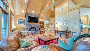 A spacious living room with a stone fireplace, leather sofas, and wooden beams on the ceiling.