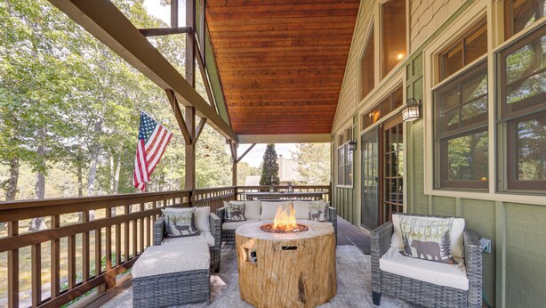 A covered outdoor seating area with wicker furniture, a central fire pit, and an American flag.