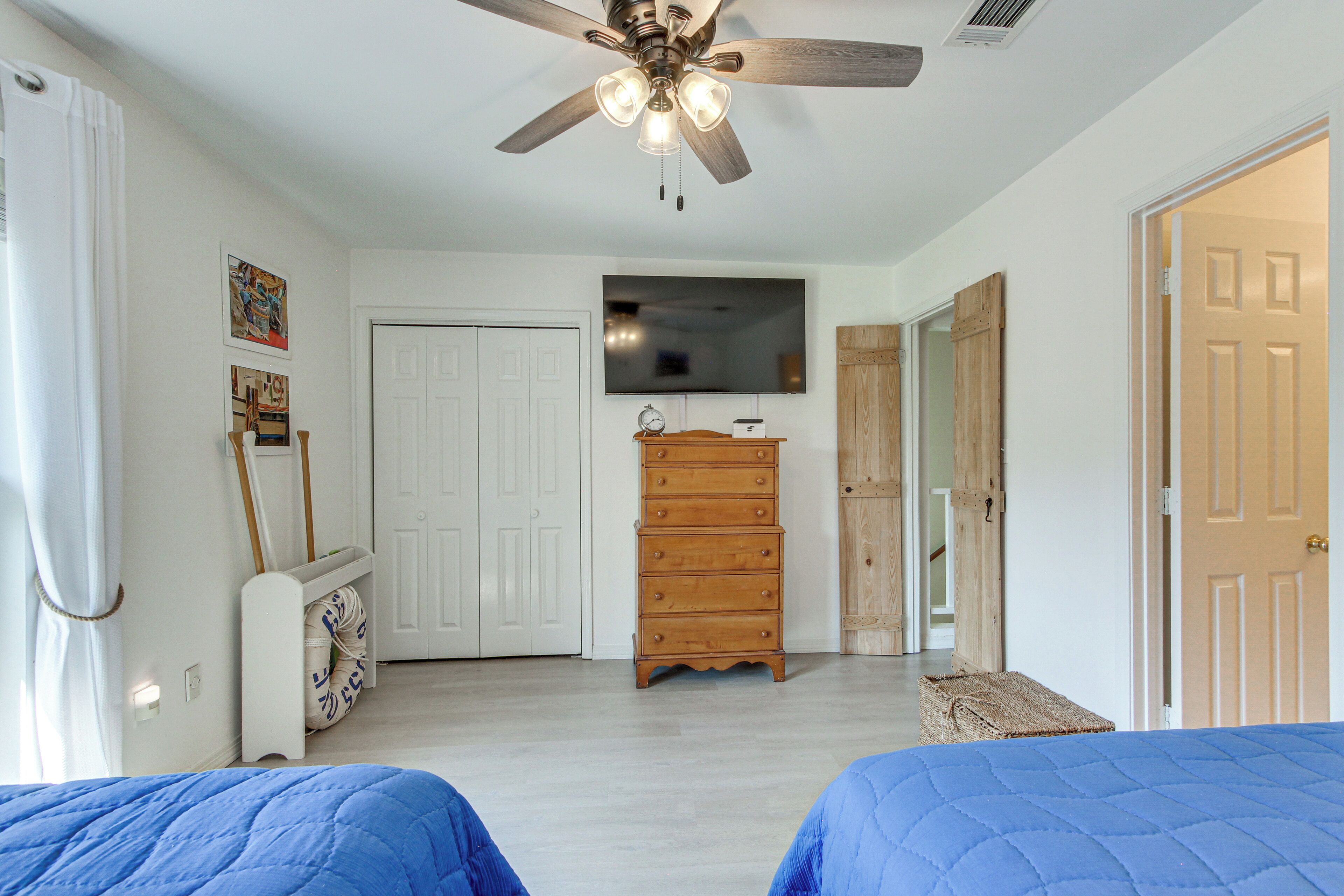 Un dormitorio con dos camas, un ventilador de techo, un aparador y un televisor.