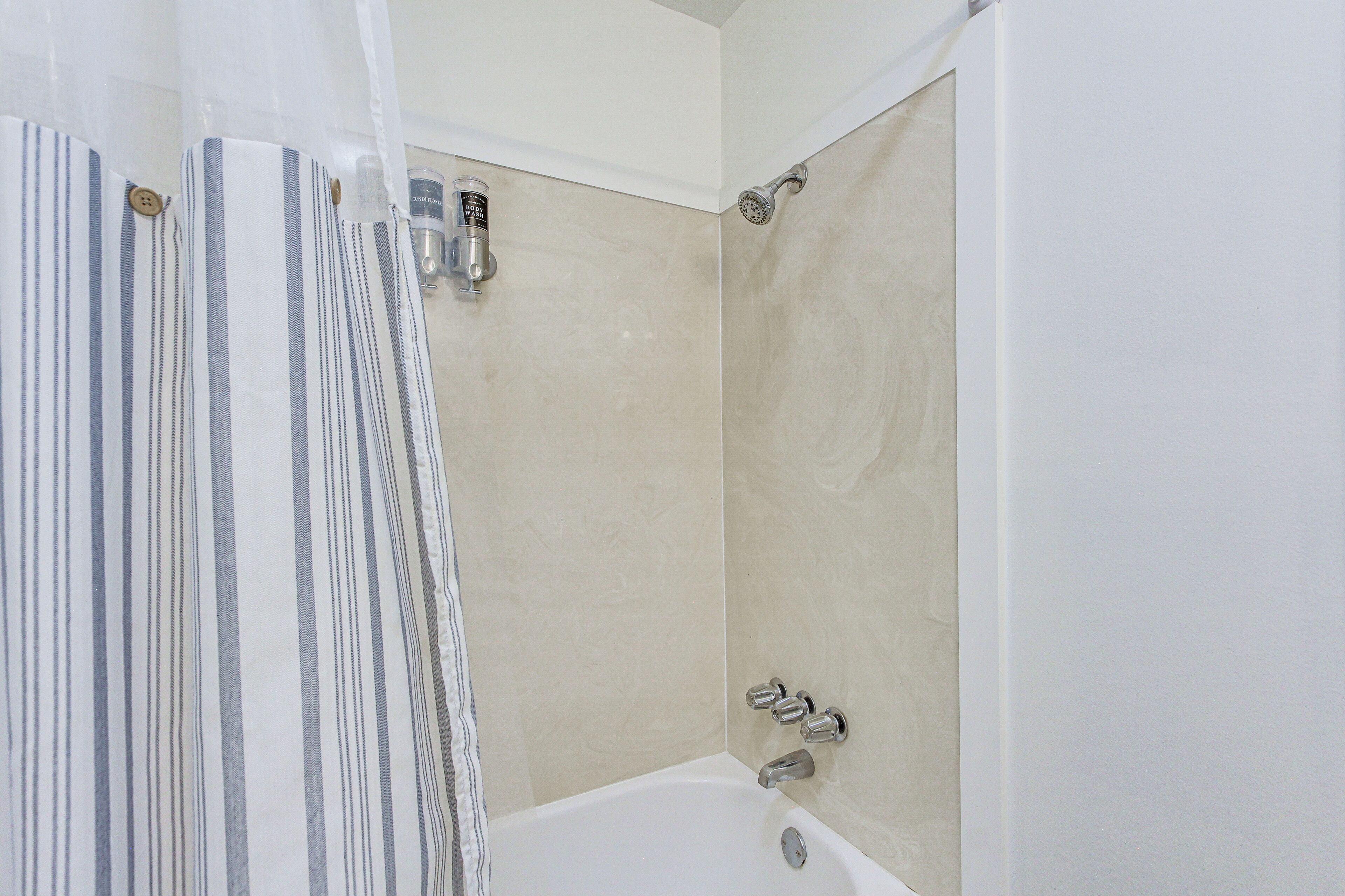 A bathroom with a bathtub, shower, and a striped curtain.