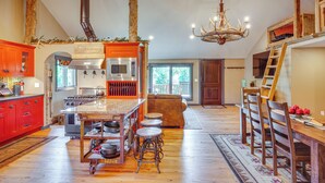 A spacious kitchen with a central island, red cabinetry, and a chandelier. - Stay & Sip: Group Ranch at Shamrock Hills Vineyard (Excelsior Springs)