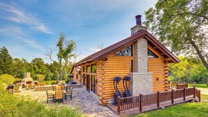 A log cabin with a stone fireplace, outdoor seating, and a stone pathway leading to the entrance. - Stay & Sip: Group Ranch at Shamrock Hills Vineyard (Excelsior Springs)
