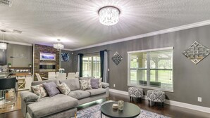 A modern living room with a grey sofa, a round coffee table, and a chandelier.