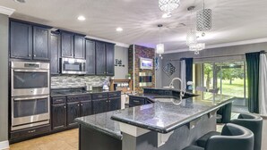 A modern kitchen with dark cabinets, stainless steel appliances, a granite island, and bar seating.