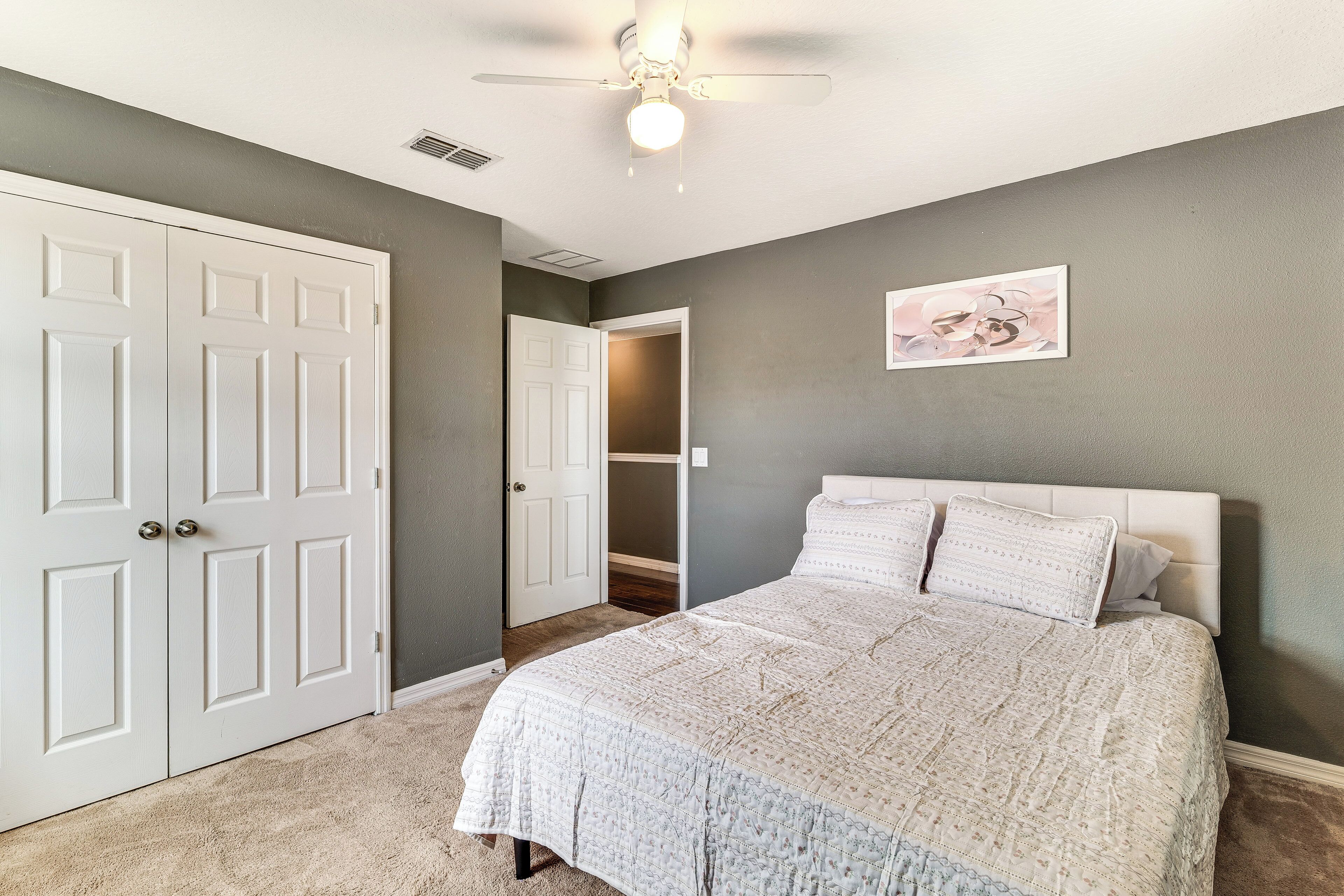 A bedroom with a bed, a ceiling fan, and a door leading to a closet.