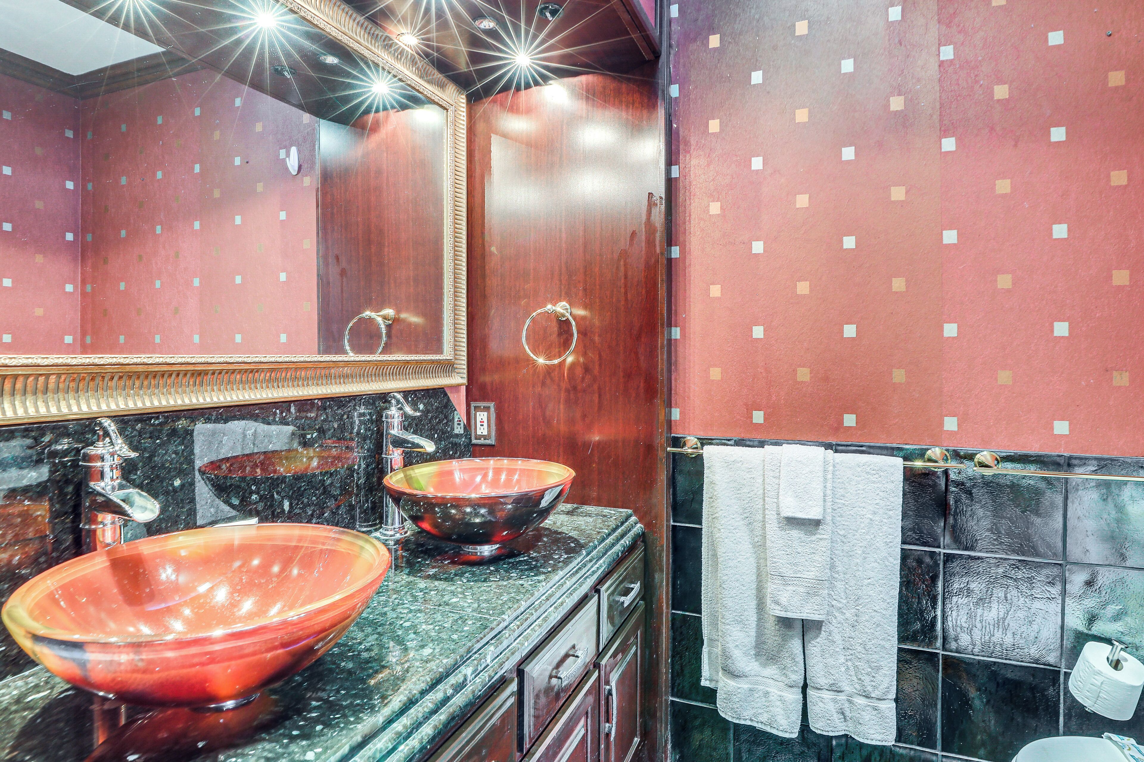A bathroom with two large glass bowls as sinks, a mirror, and a towel rack.