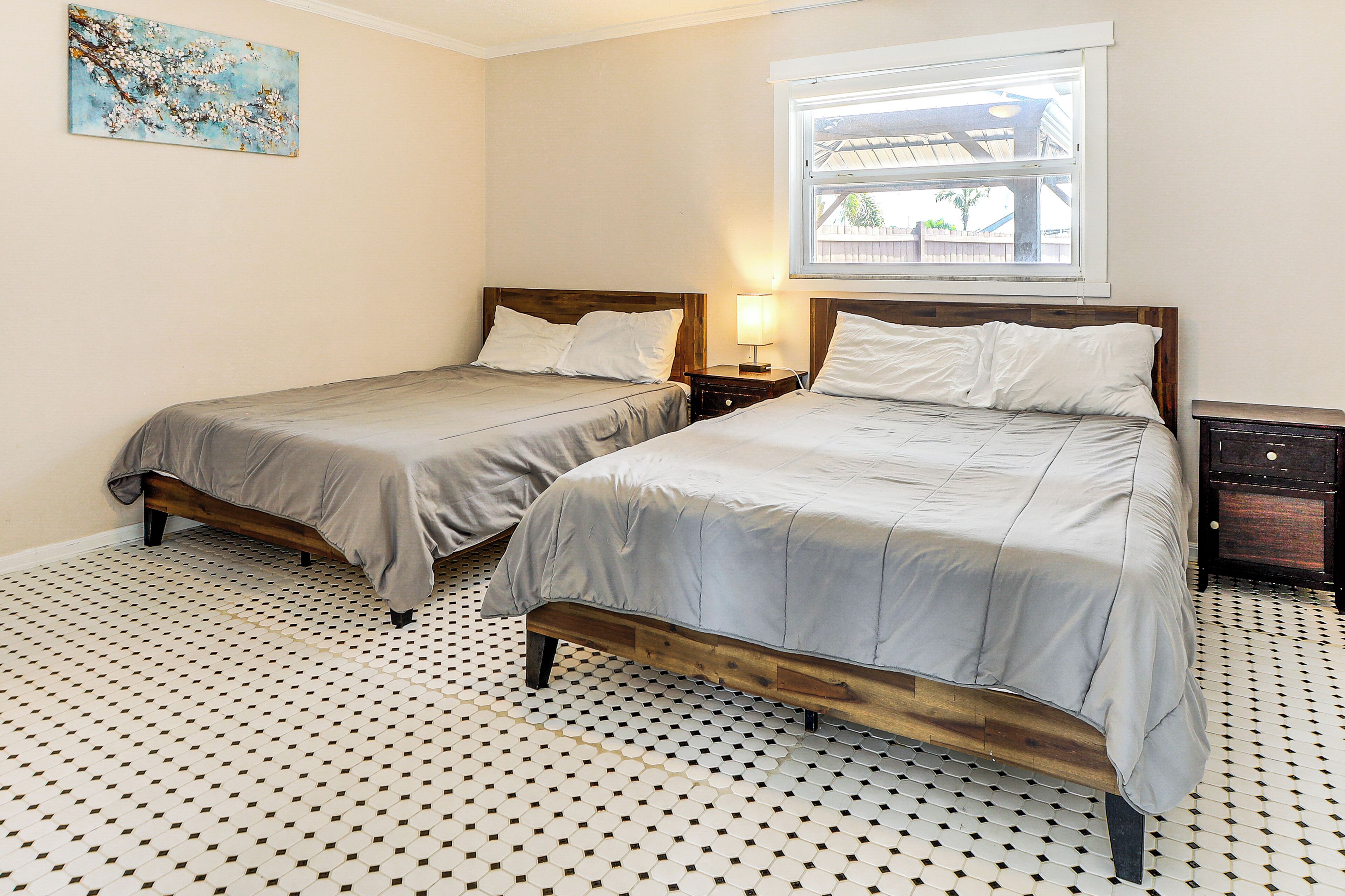 Une chambre avec deux lits, une fenêtre et un sol à motifs.