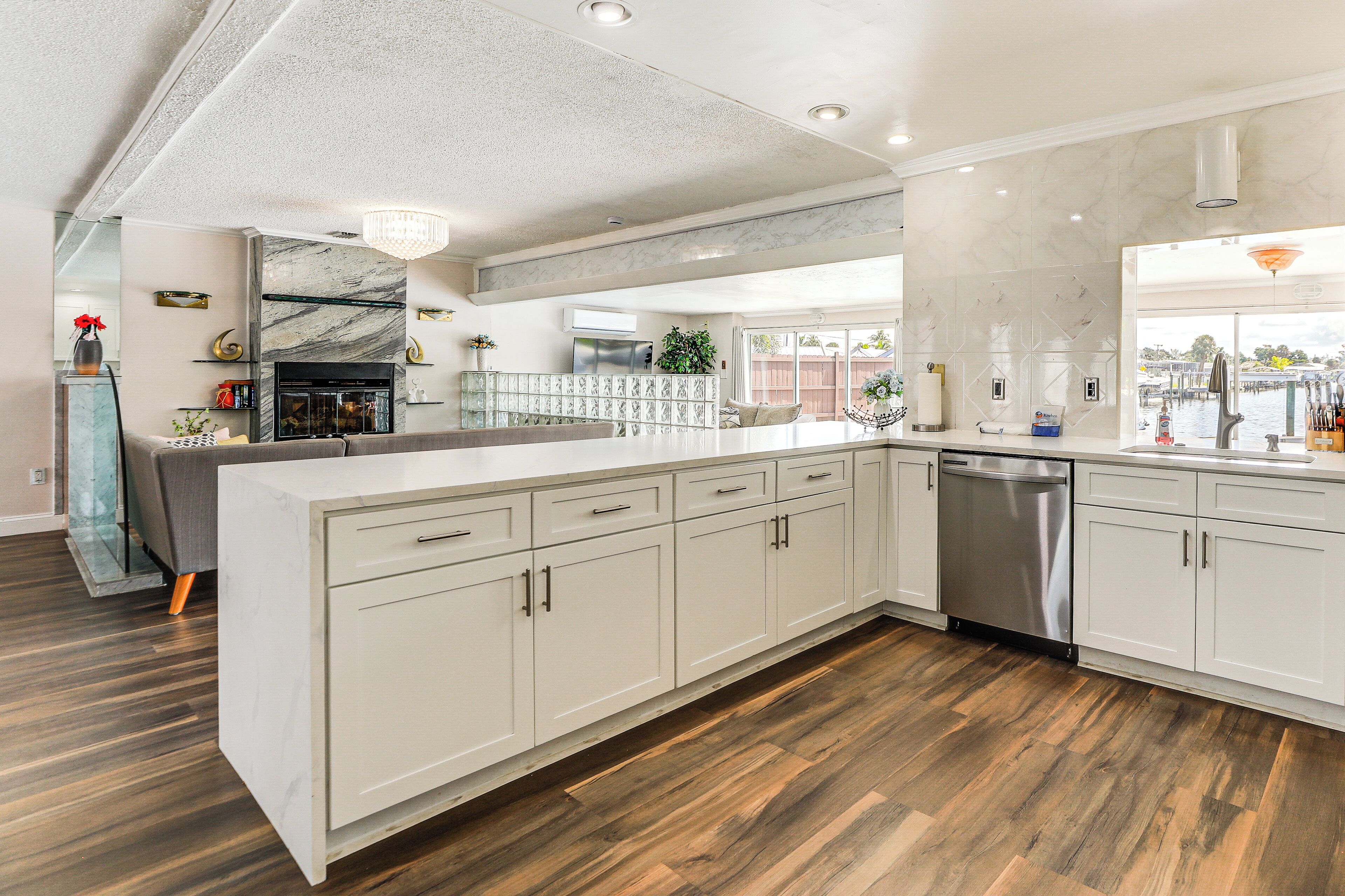 A modern kitchen with white cabinetry, a large island, and a dishwasher.