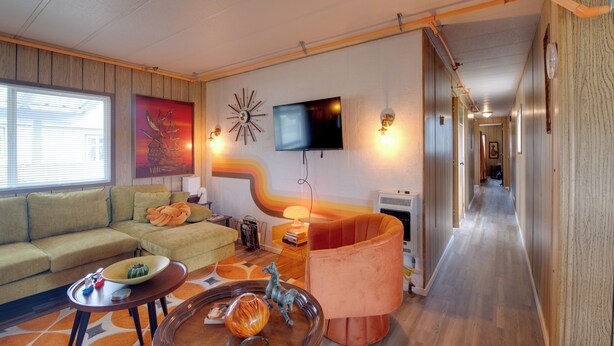 A living room with a sofa, a coffee table, and a TV mounted on the wall. - Walk to Beach! Fun Retro Retreat in Ocean Shores (Ocean Shores)