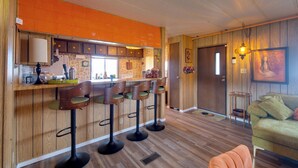 A kitchen with wooden cabinets, a bar area with stools, and a dining table. - Walk to Beach! Fun Retro Retreat in Ocean Shores (Ocean Shores)