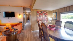 A dining area with a wooden table, chairs, and a wall with a colorful fruit pattern. - Walk to Beach! Fun Retro Retreat in Ocean Shores (Ocean Shores)