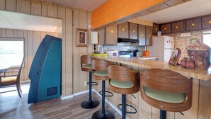 A kitchen with wooden cabinets, a countertop, and bar stools. - Walk to Beach! Fun Retro Retreat in Ocean Shores (Ocean Shores)