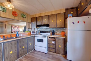 Una cocina con armarios de madera, estufa blanca, microondas y refrigerador.