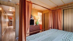 A hotel room with a large bed, wooden walls, a dresser, a television, and a lamp. - Walk to Beach! Fun Retro Retreat in Ocean Shores (Ocean Shores)