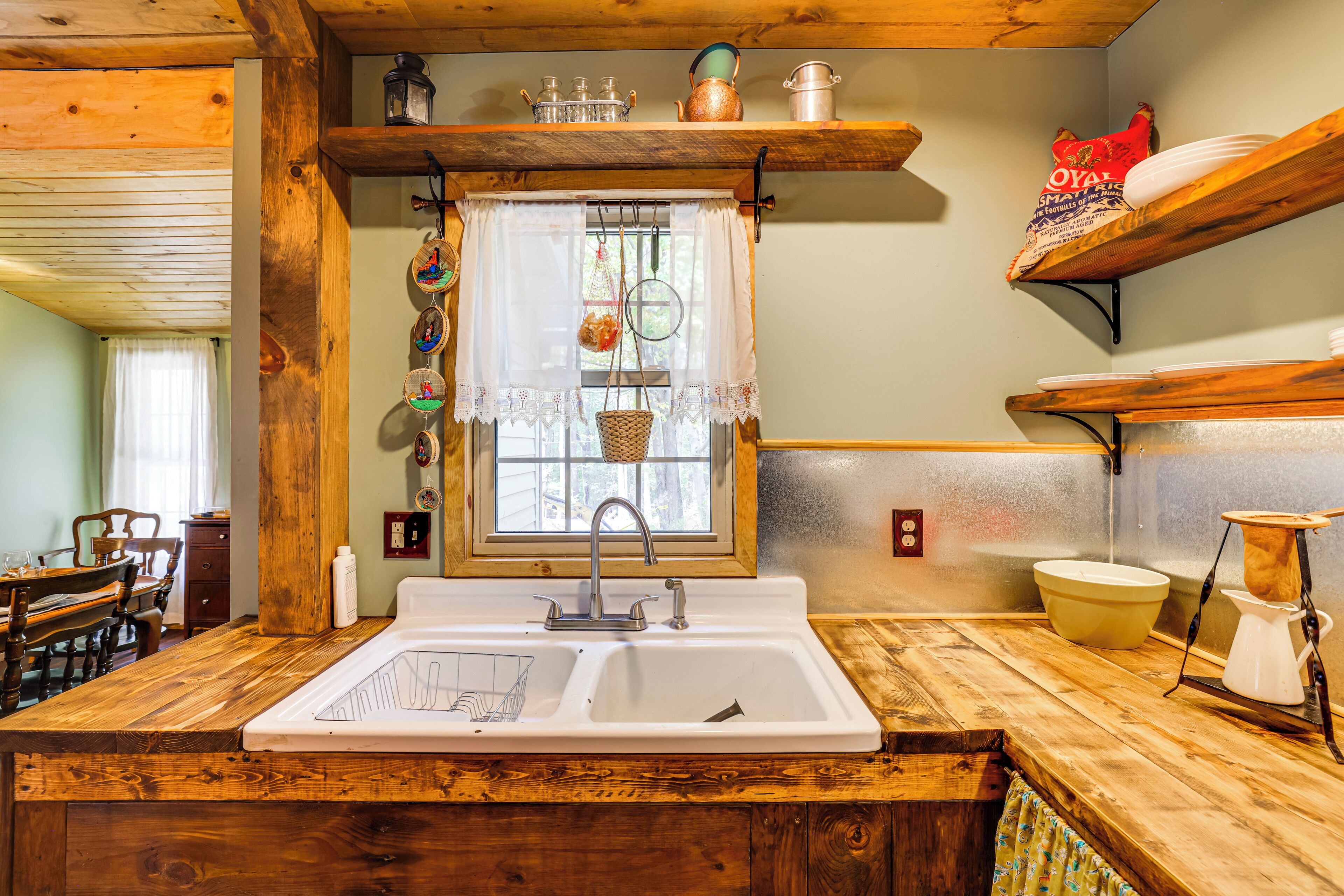 Une cuisine dotée de plans de travail en bois, d’un évier à deux bacs et d’une fenêtre agrémentée d’objets décoratifs.