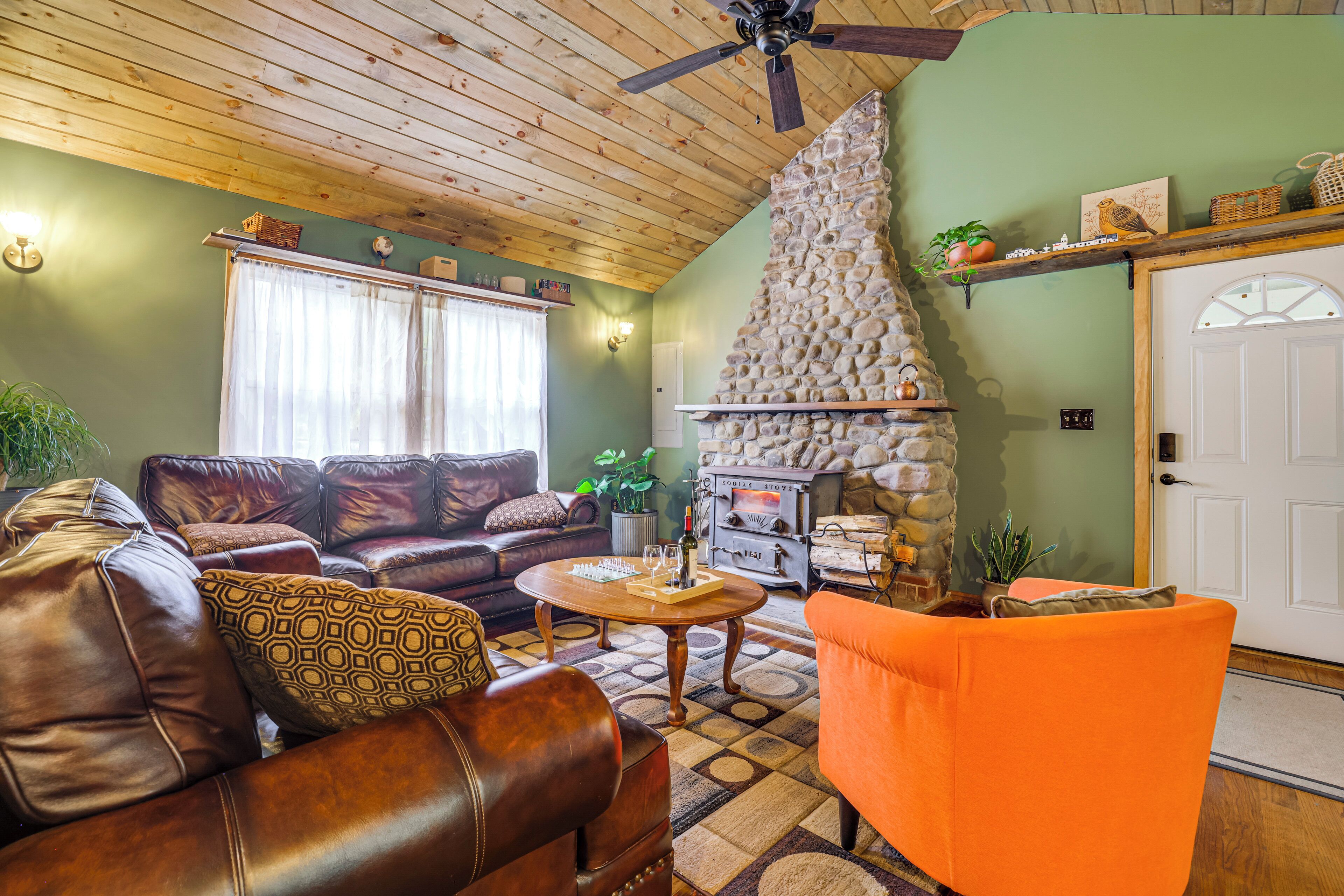 A cozy living room with leather sofas, a stone fireplace, and a wooden ceiling.