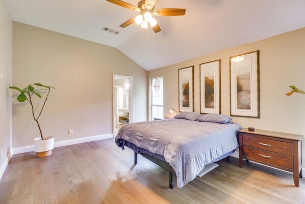 A bedroom with a bed, bedside table, nightstand, and a ceiling fan.