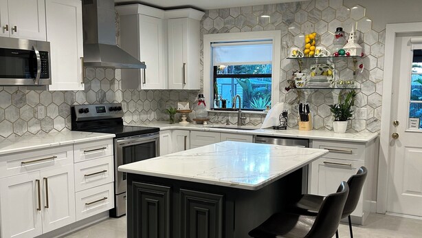 A modern kitchen with white cabinetry, a central island with bar stools, a built-in microwave, and a window with a view.
