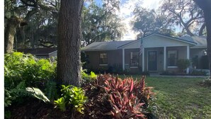 A house with a front yard, surrounded by trees and plants.